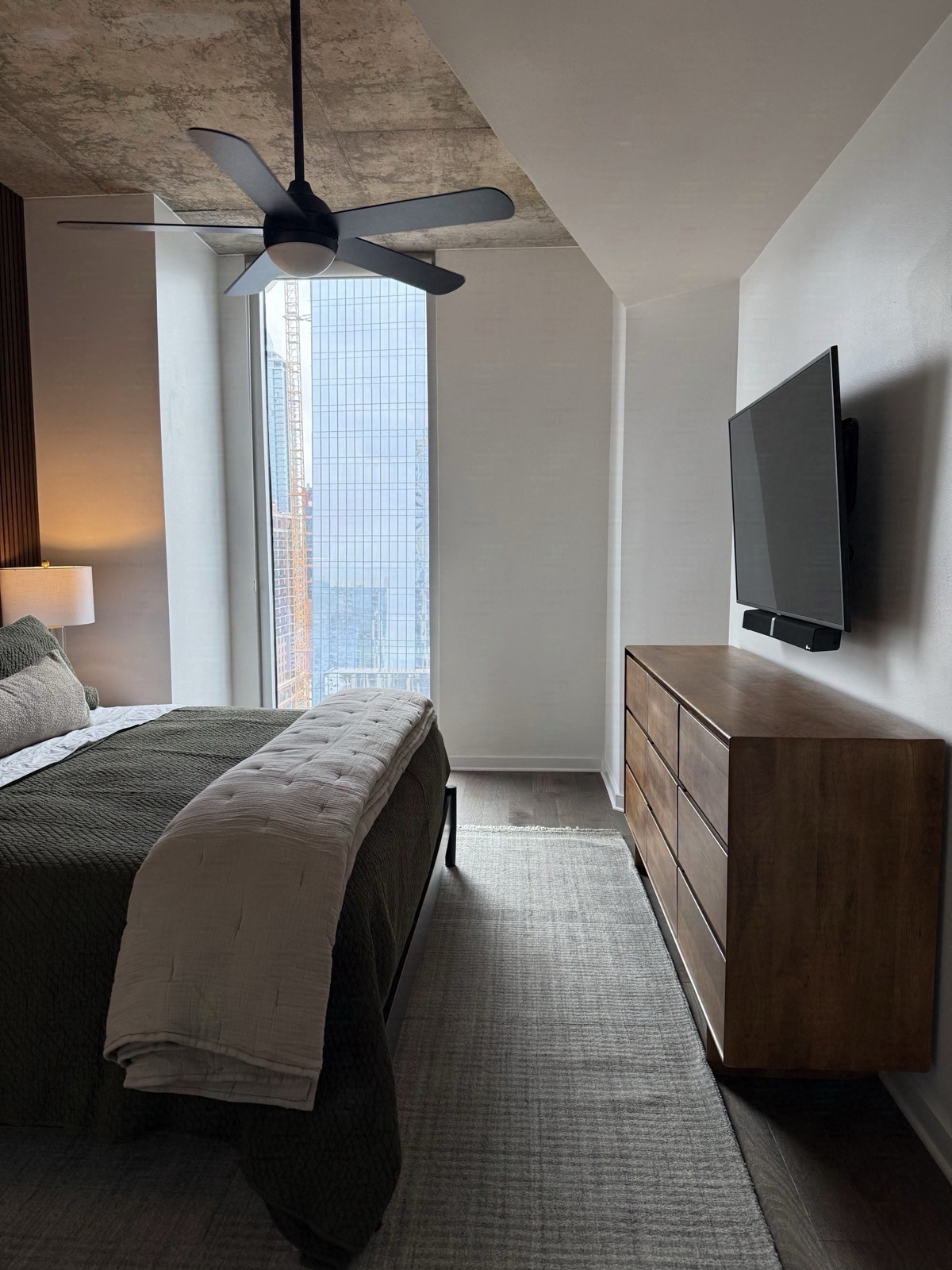 Bedroom with a low platform bed, walnut dresser and a floor-to-ceiling window overlooking the city, designed by Refinery ATX in Austin, TX