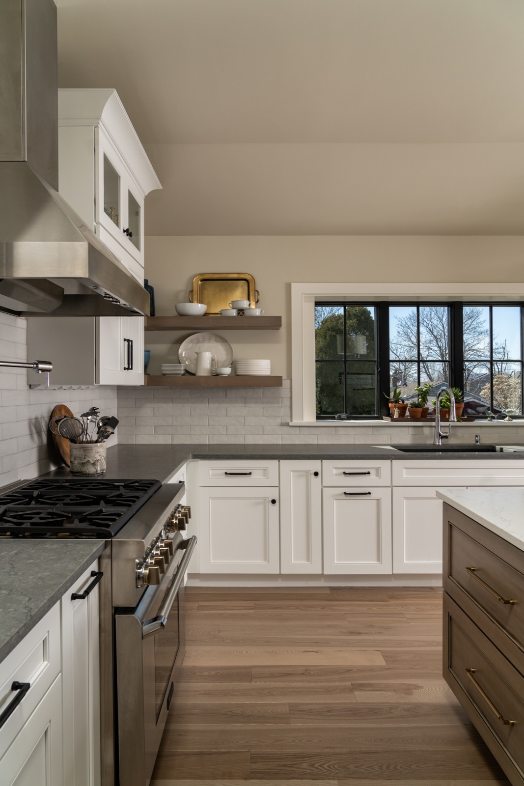 White kitchen with a professional gas range, subway tile and open wood shelving by Refinery ATX in Austin, TX