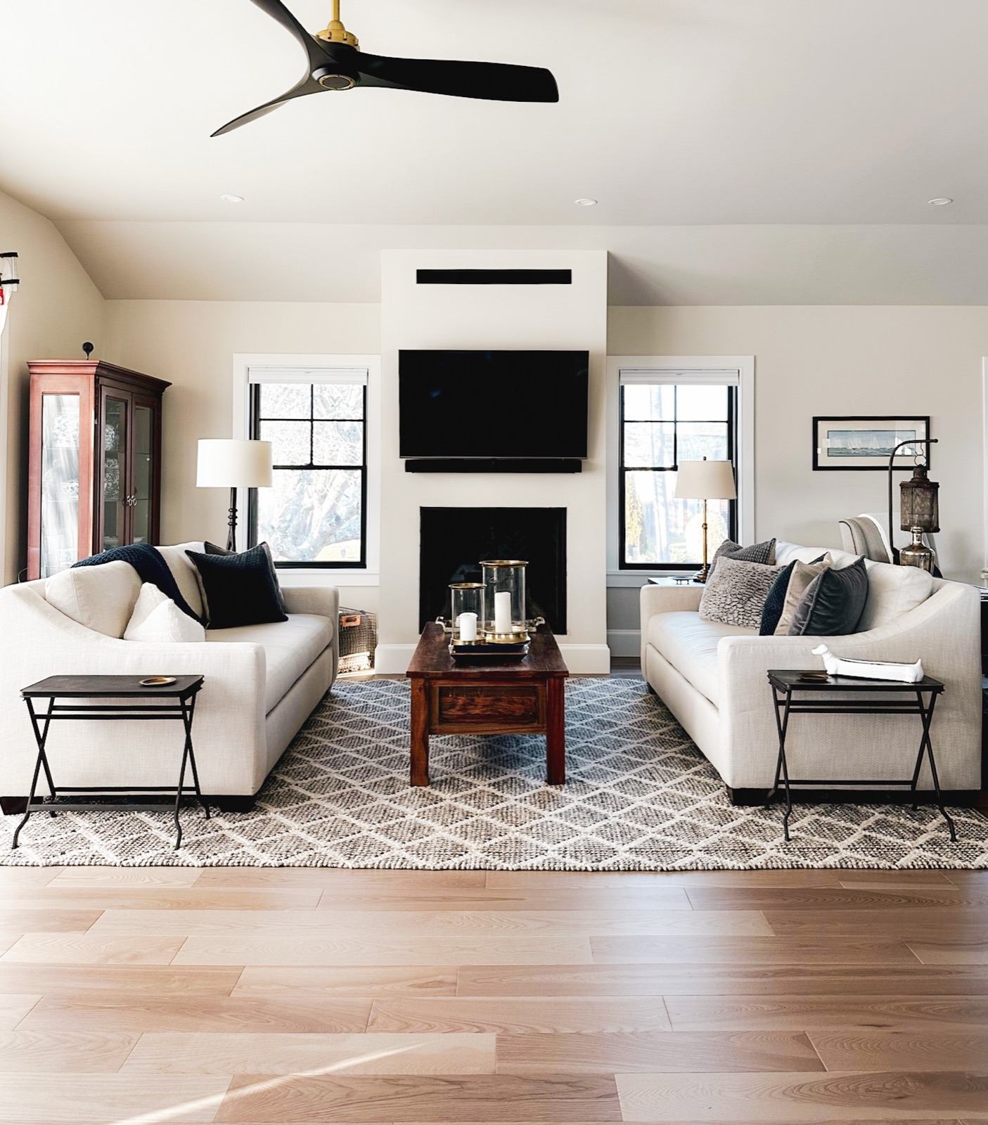 Living room with two facing sofas, a fireplace flanked by black-framed windows and a patterned area rug, in Austin, TX